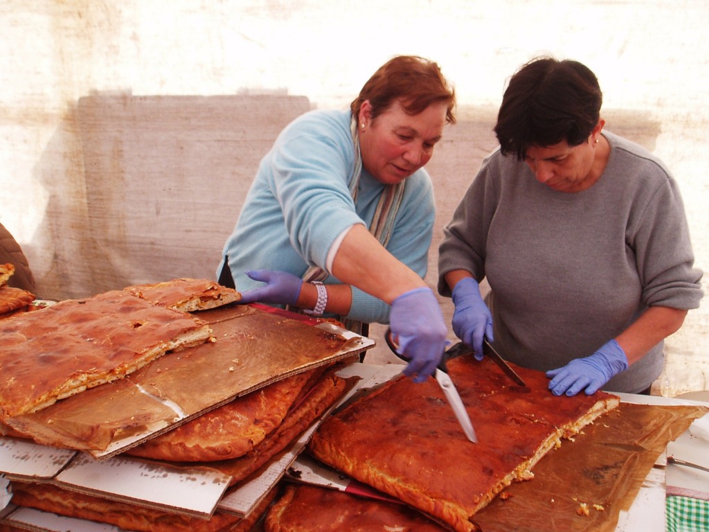 Dos mujeres de la organización cortando la empanada