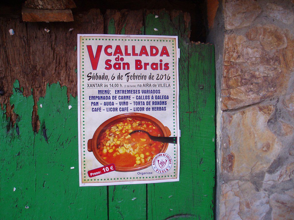 Cartel de la fiesta pegado en la puerta de una casa antigua de Vilela