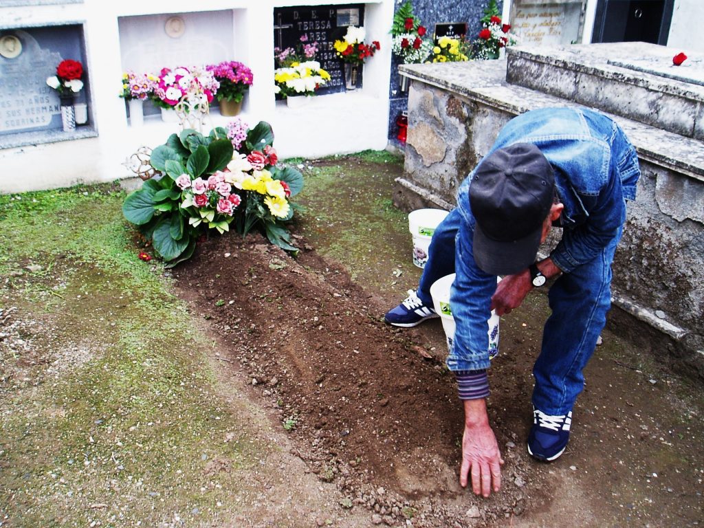 Acondicionando una tumba en tierra el día de santos en A Rúa Vella