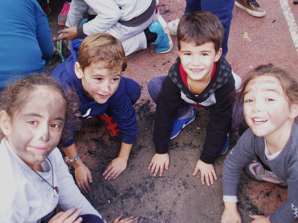 Cuatro niños en el suelo para pintarse con hollín