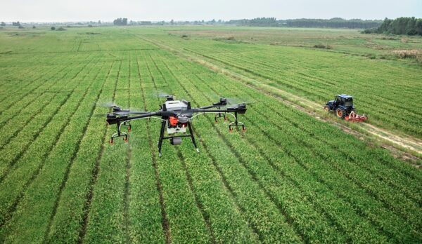 Dron sobrevolando un campo agrícola, monitoreando cultivos con tecnología avanzada para optimizar la producción.