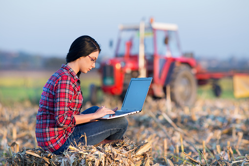 Mujer trabajando en el campo con herramientas modernas en un paisaje rural que combina tradición e innovación."